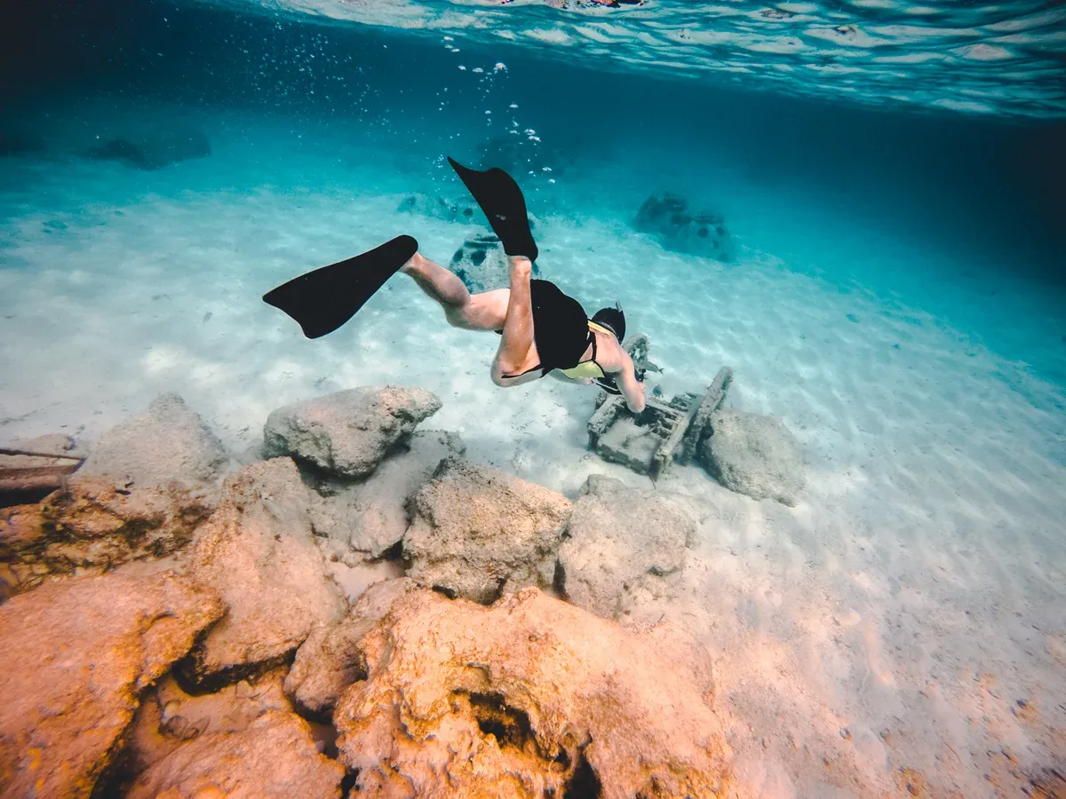 Snorkeller in fins over a Bahamas reef, the gear to think about when deciding what to pack for a Bahamas cruise
